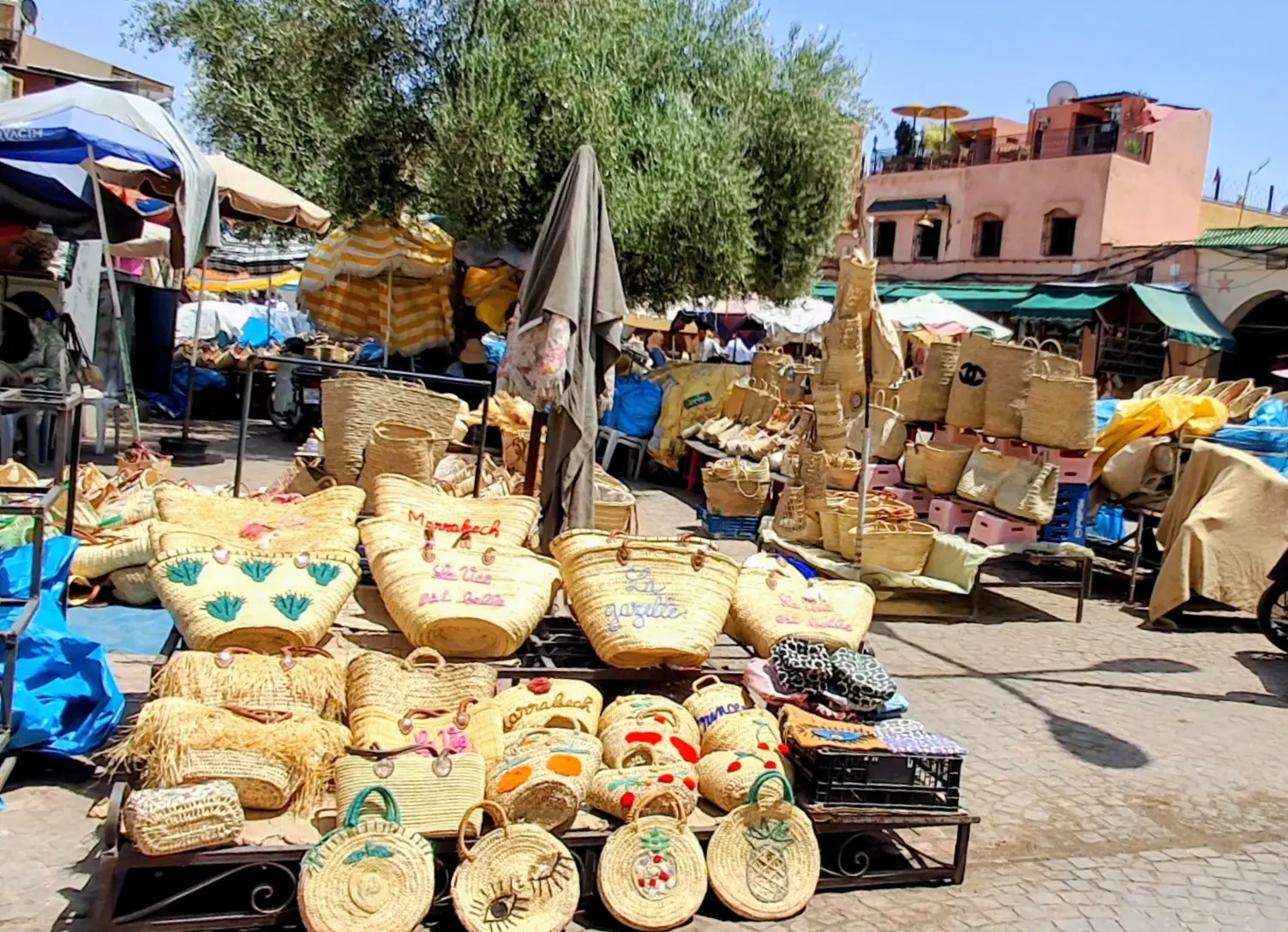 Étal en plein air de paniers et cabas en osier tressé sur une place animée des souks de Marrakech.
